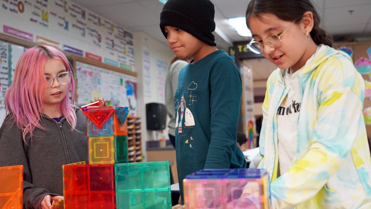 three students building colorful castle